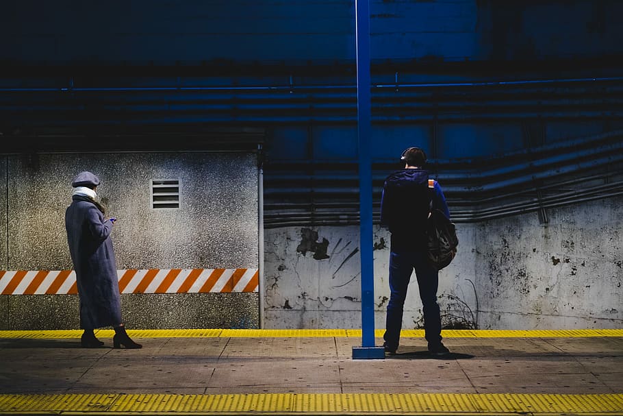 man standing near post, two people standing in subway station HD wallpaper