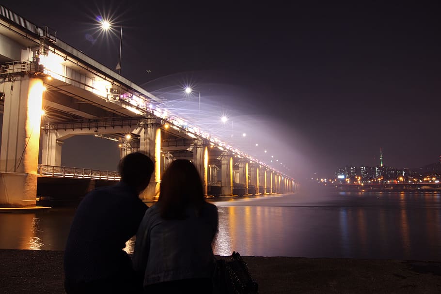 man and woman near lighted bridge and ocean during nighttime, HD wallpaper