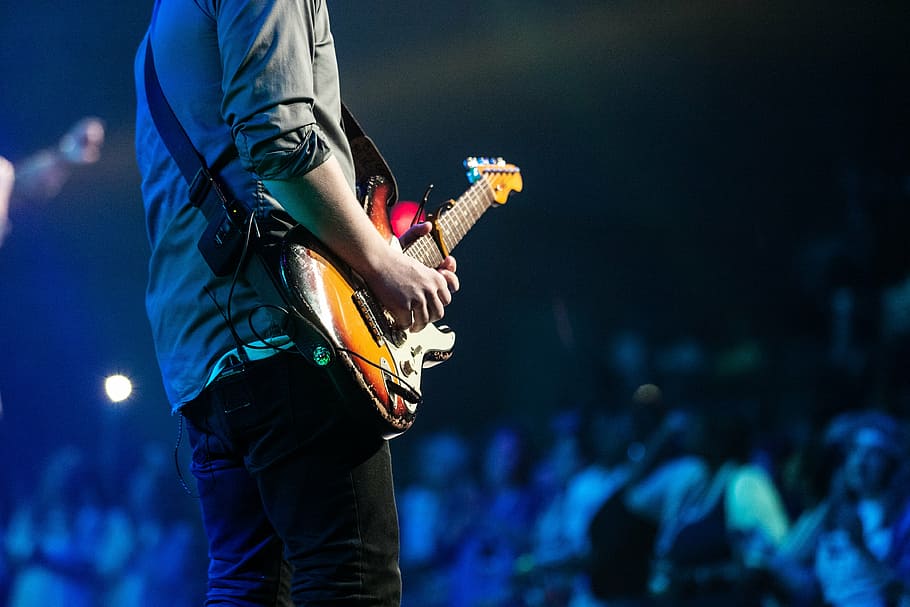 shallow focus photography of man holding electric guitar, selective
