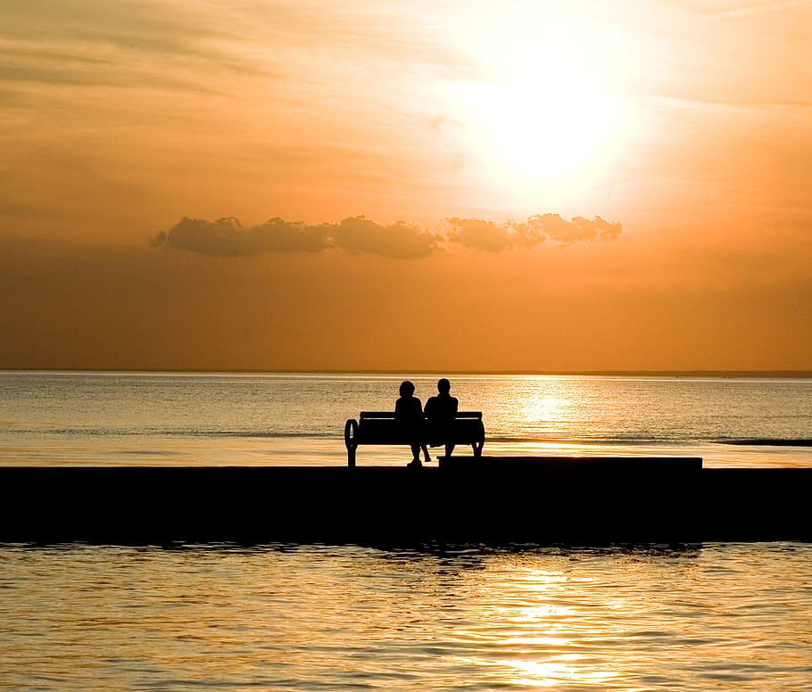 silhouette of two person sitting on bench near body of water during daytime, HD wallpaper
