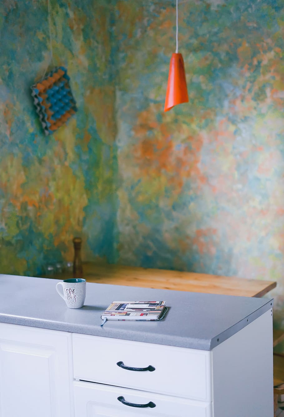 book beside mug on top of dresser, red pendant lamp above grey and white dresser inside room HD wallpaper