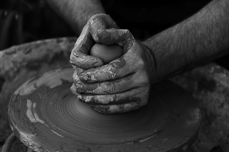 grayscale photography of person's hand making pot, person holding a clay