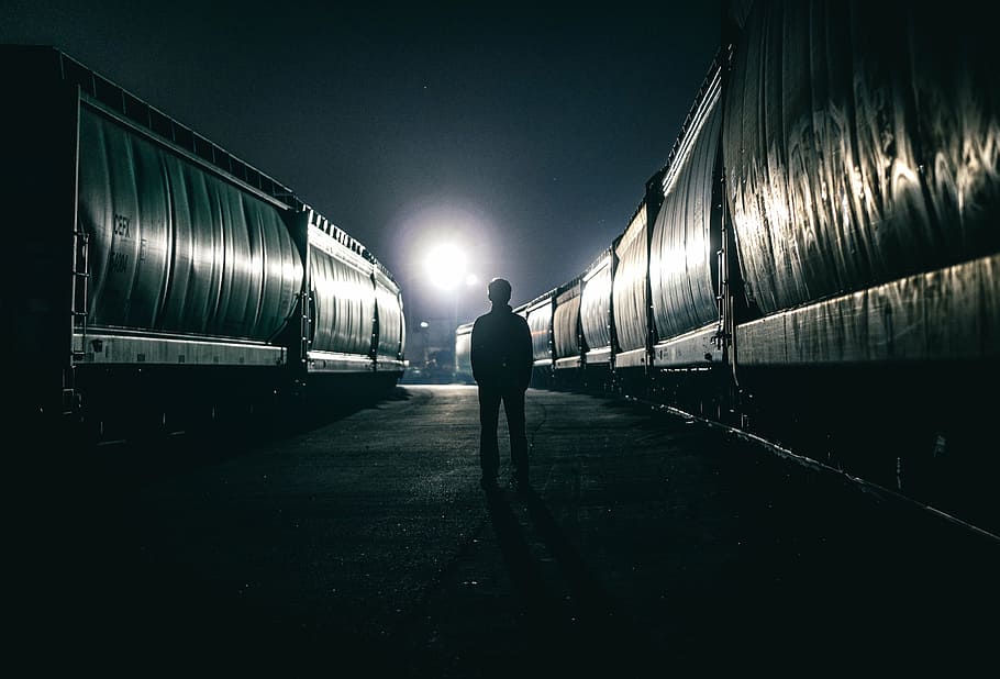 silhouette of man standing in between vehicles during night, dark
