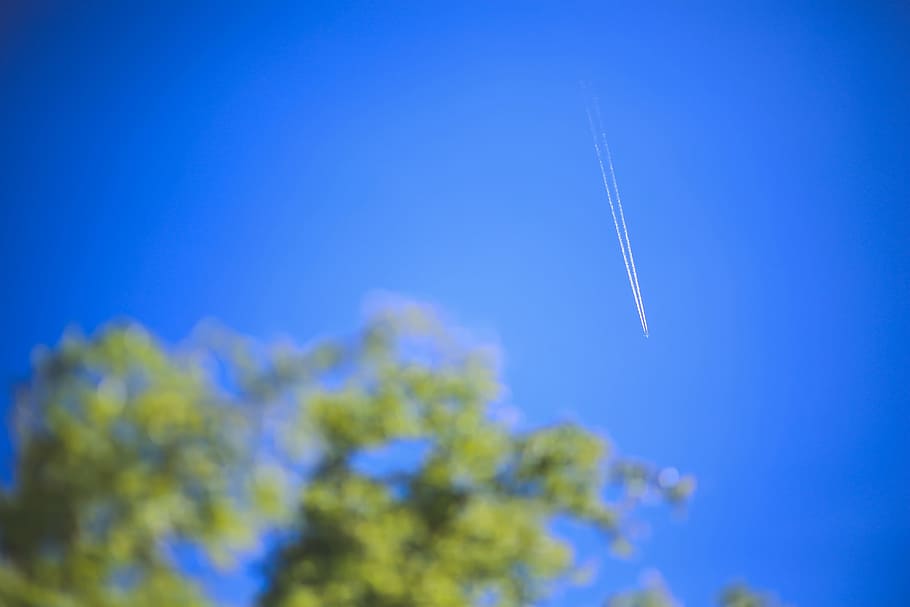 Passenger jet flying high in clear blue sky, leaving long white trail