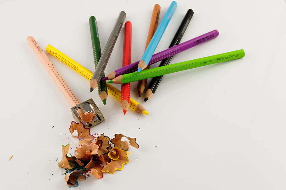sharpened color pencil and pile of color pencils on white surface