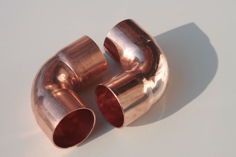 two copper-colored elbow pipes on white surface, fittings, shine