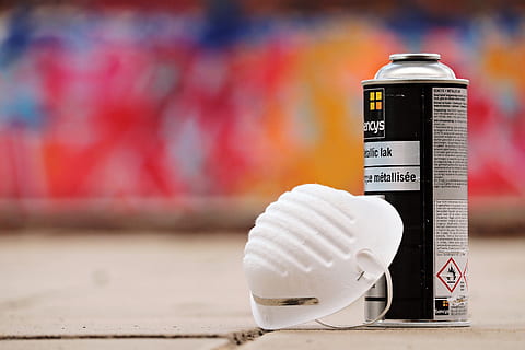 selective focus photo of white face mask and spray paint bottle on top of beige surface HD wallpaper