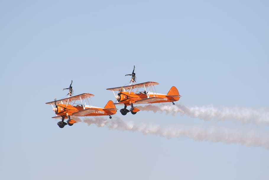 photo of two orange flying biplanes, two orange airplanes on sky HD wallpaper