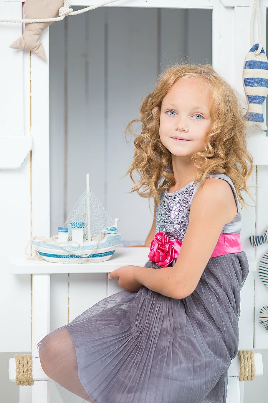 girl wearing gray and pink sleeveless dress, young, room, white