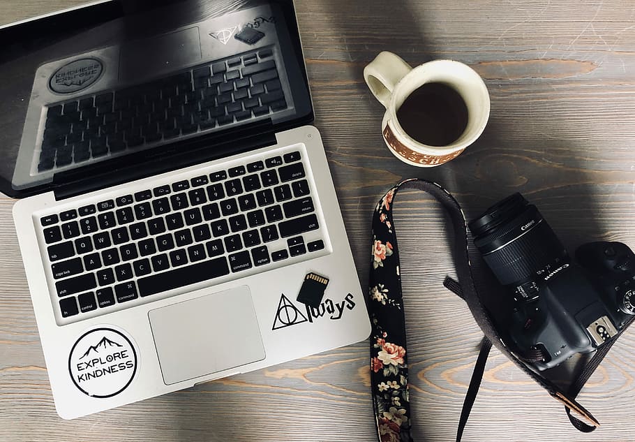 black and gray laptop computer beside black DSLR camera and white ceramic mug, MacBook Pro on brown wooden panel HD wallpaper