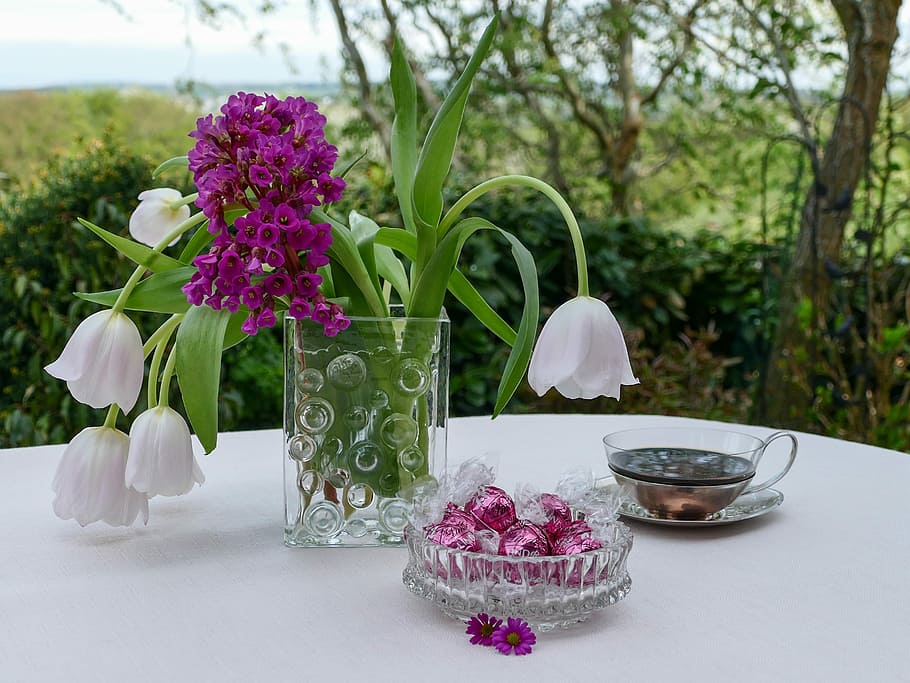 white and purple flower centerpiece near tea cup on white table