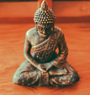 Gautama Buddha figurine on brown wooden surface, selective focus photography of Gautama Buddha figurine HD wallpaper