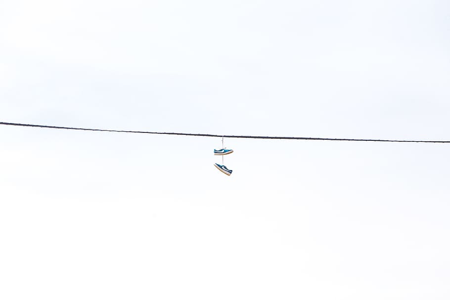 pair of green low-top sneakers hanged on wire, pair of blue sneakers hanging on cable