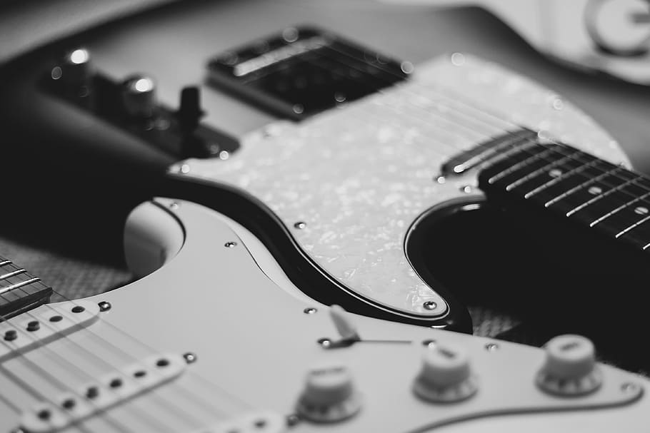 black and white photo of two stratocaster electric guitars, selective focus grayscale photography of two electric guitars
