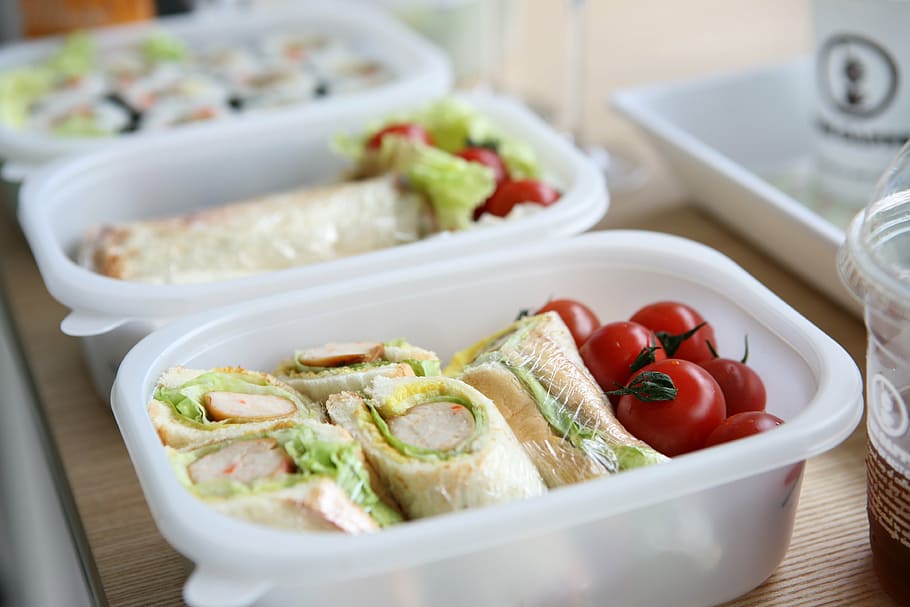 two white plastic containers with sandwich and tomatoes, lunch box