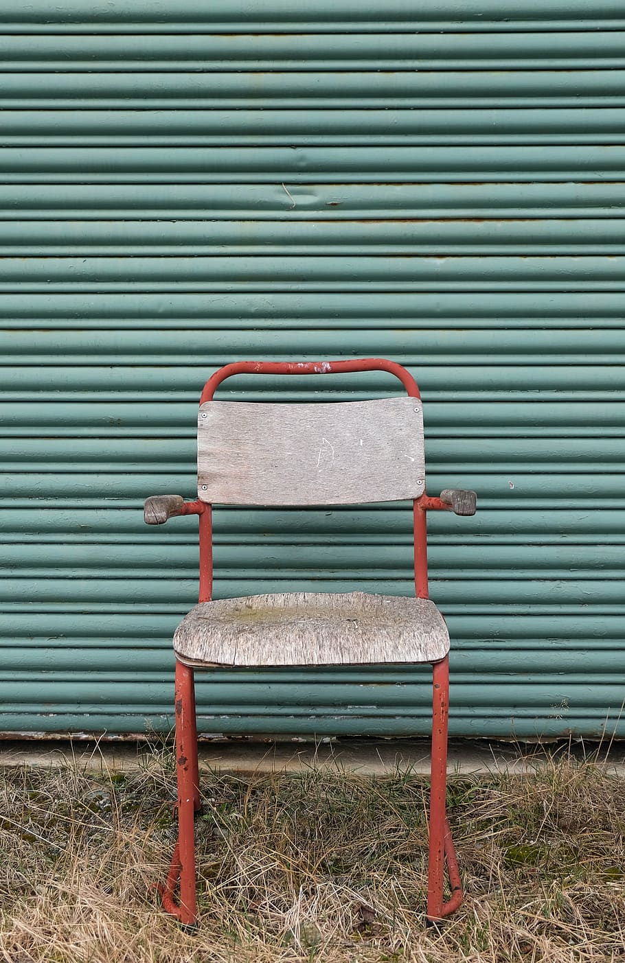 armchair in front of roller shutter, red, gray, padded, beside