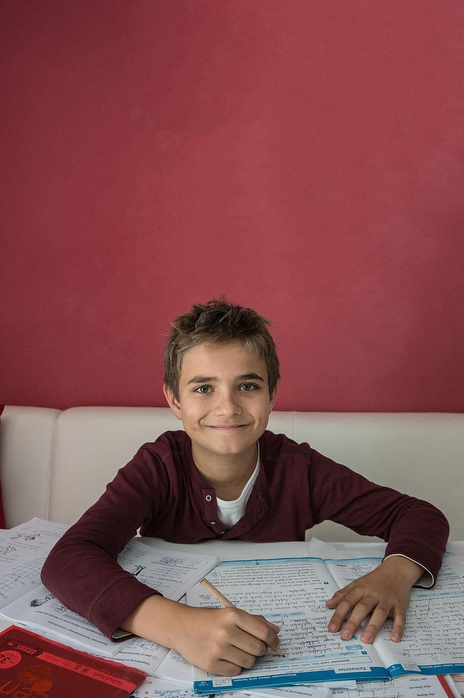 boy sitting on sofa in front of table while smiling and holding pen HD wallpaper