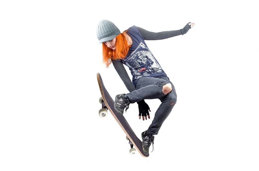 woman in black long sleeve shirt ,pants and pair of shoes  jumping with skateboard on feet