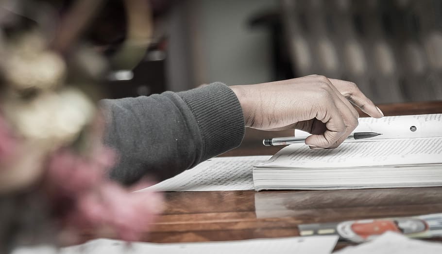 person putting pen on book, person holding pen during daytime HD wallpaper