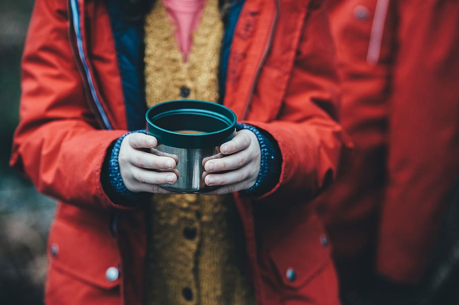 shallow focus photography of person holding green plastic container, person in red zip-up jacket holding silver stainless steel cup filled with coffee, HD wallpaper