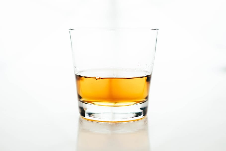 clear rock glass filled with yellow liquid, clear shot glass filled with yellow liquid in selective focus photography