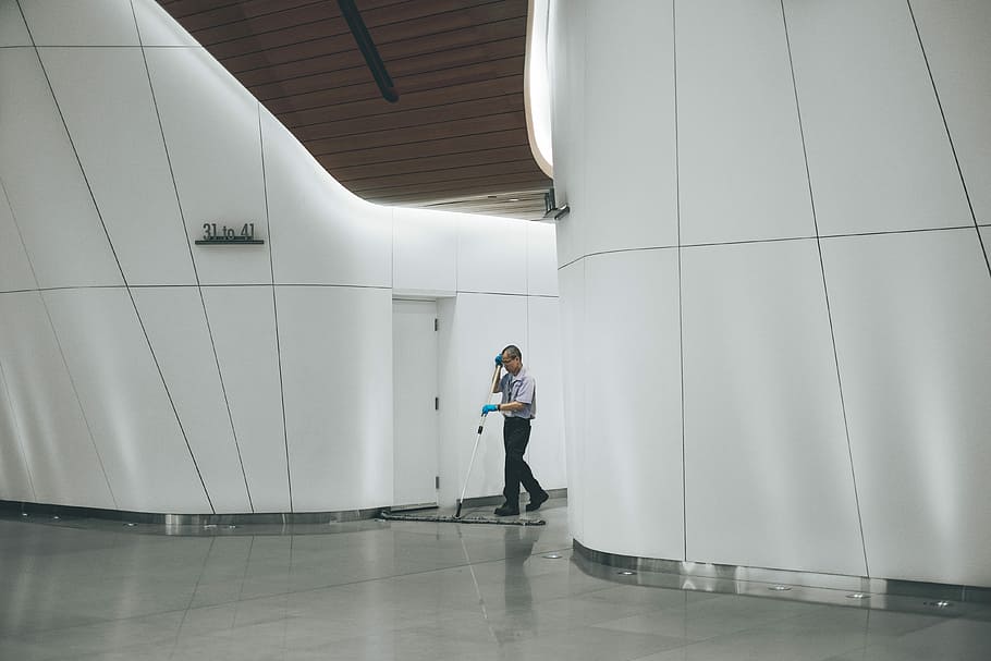 man cleaning on floor beside white wall, man mopping floor inside well-lit room