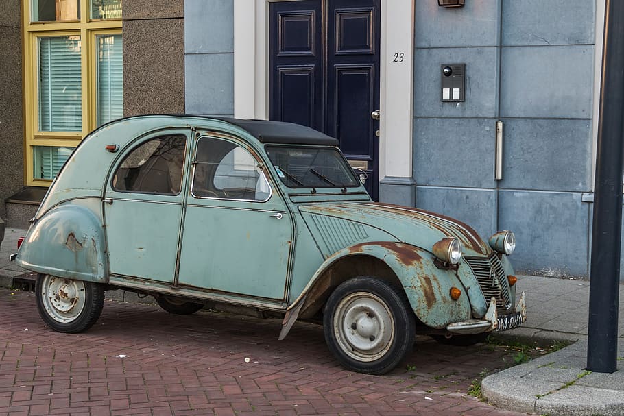 teal Volkswagen Type 1 parked beside blue and gray concrete building at daytime HD wallpaper