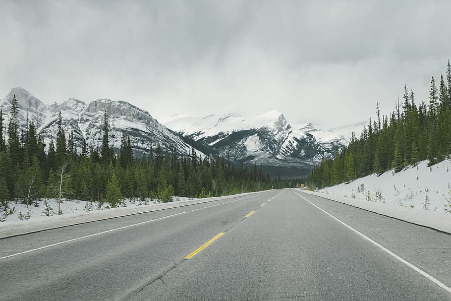 snowy mountains across asphalt road, photo of asphalt road towards mountain alps