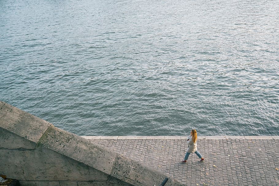 Walking alone beside the Seine, woman walking near body of water during daytime HD wallpaper