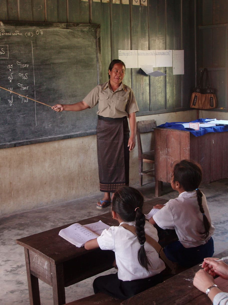 woman standing inside room beside chalkboard, students, primary school