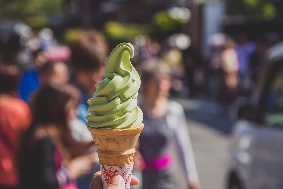 person's hand holding green icecream with cone, asia, background