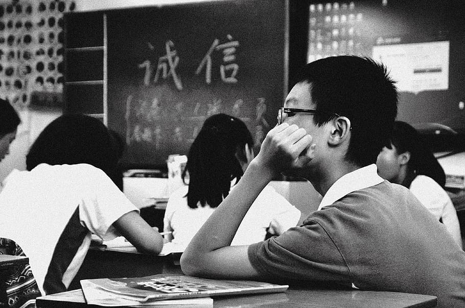 grayscale photo of boy inside classroom, students, school, sad