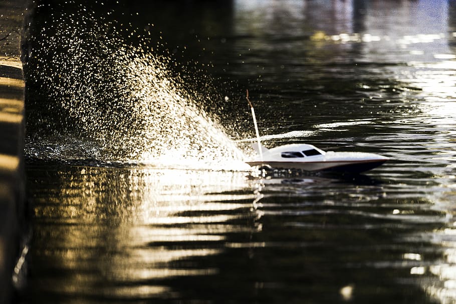 macro shot photography of white remote controlled boat toy, white R/C power boat on body of water