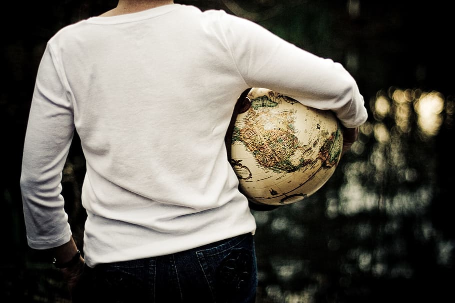 man wearing white long-sleeved shirt carrying globe, traveller HD wallpaper