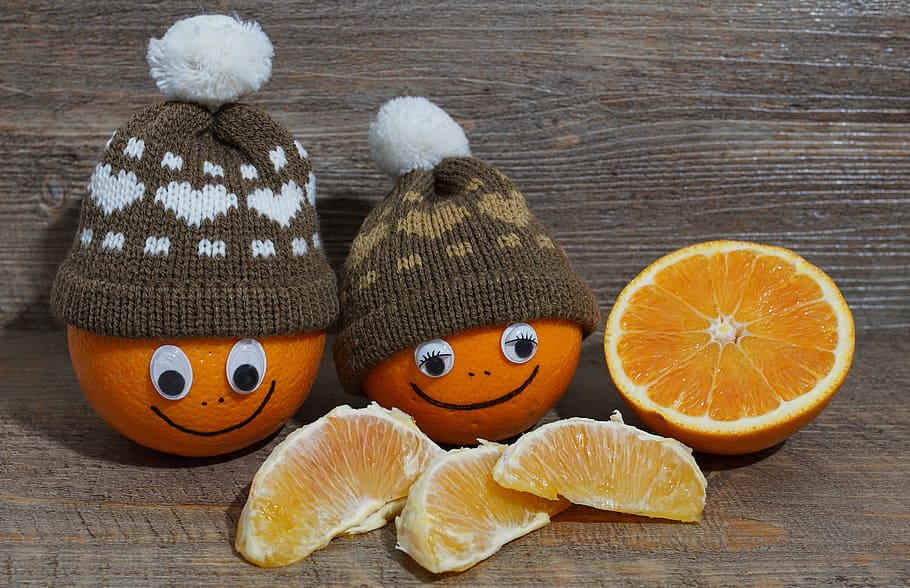 two orange with brown bobble caps beside sliced orange fruit