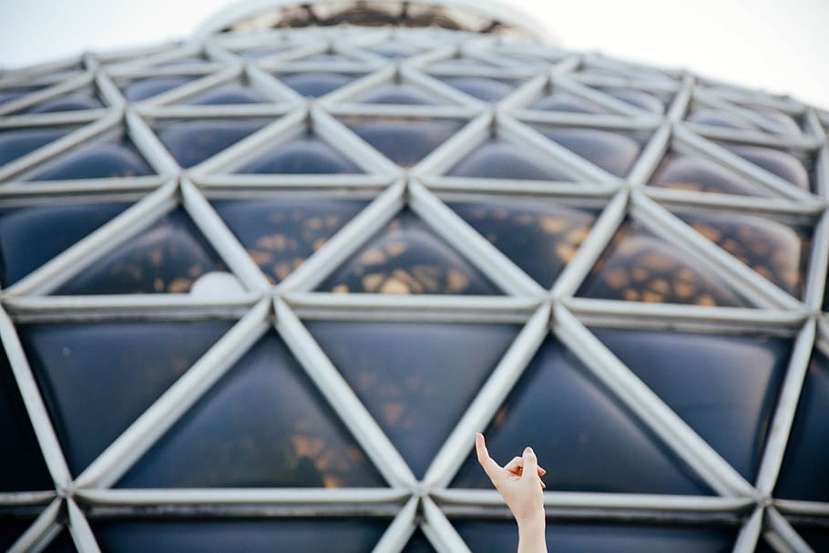closeup photo of person pointing glass roof, selective focus photography of white dome building HD wallpaper