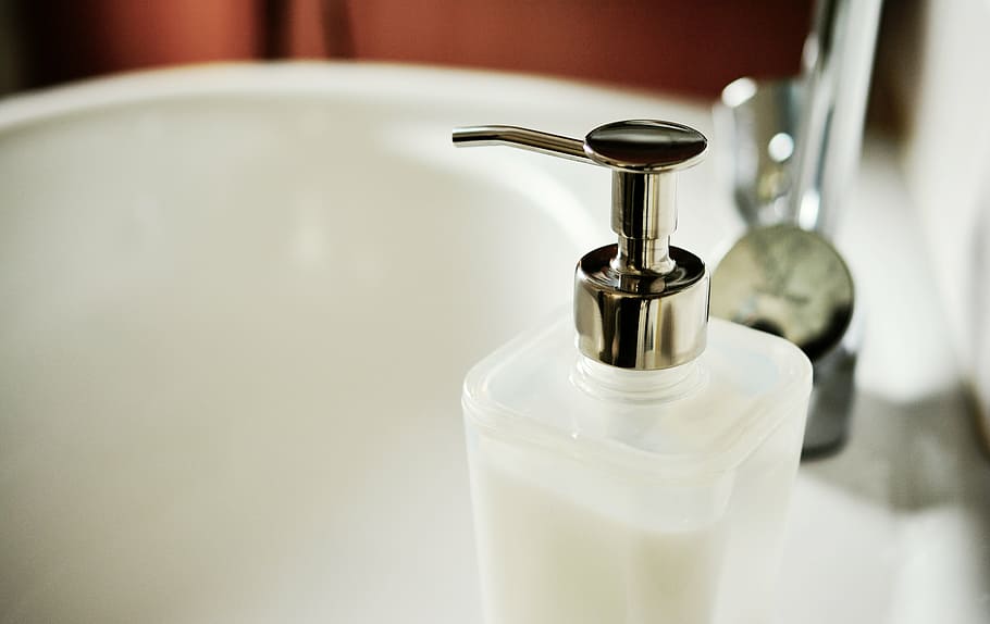 clear glass pump bottle on ceramic sink, soap dispenser, liquid soap