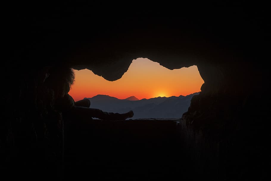silhouette of person sitting on cave during golden hour, silhouette of cave HD wallpaper