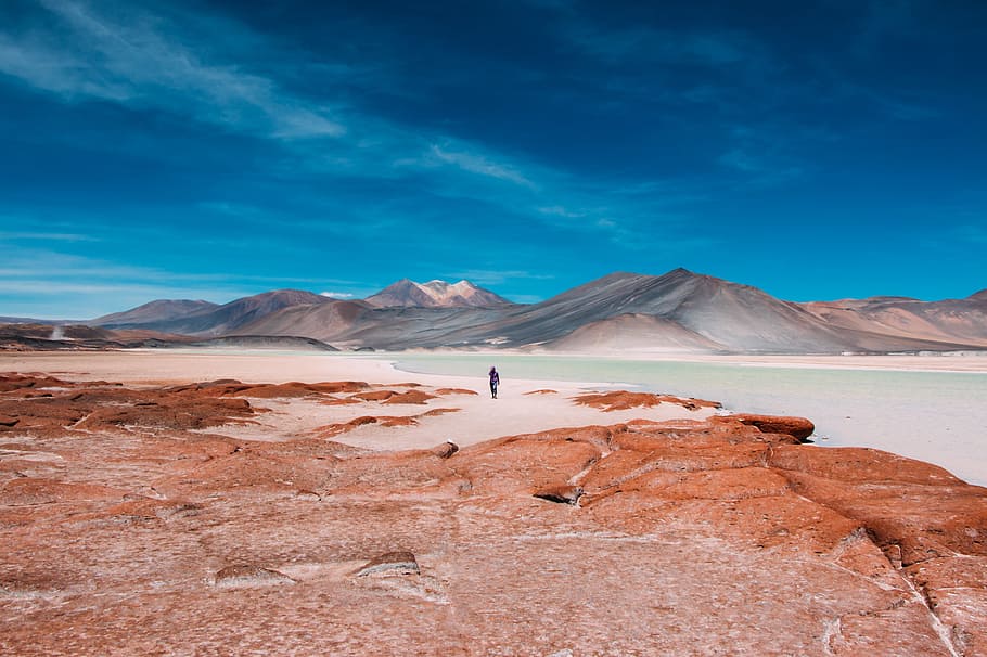 person walking in distance of mountain, silhouette person standing on sand bank HD wallpaper