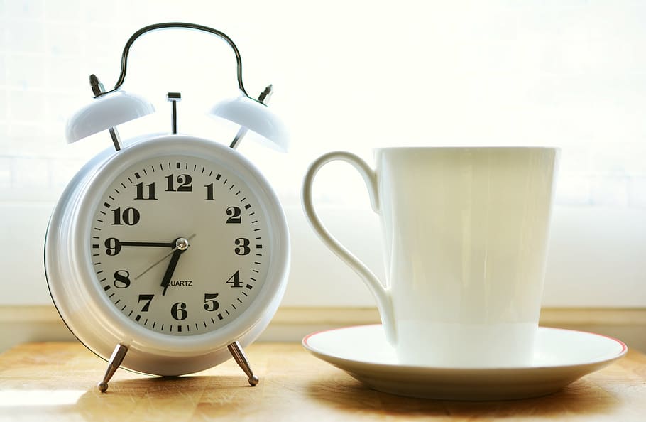 closeup photo of white ceramic mug on saucer beside white twin-bell alarm desk clock on brown wooden table, HD wallpaper