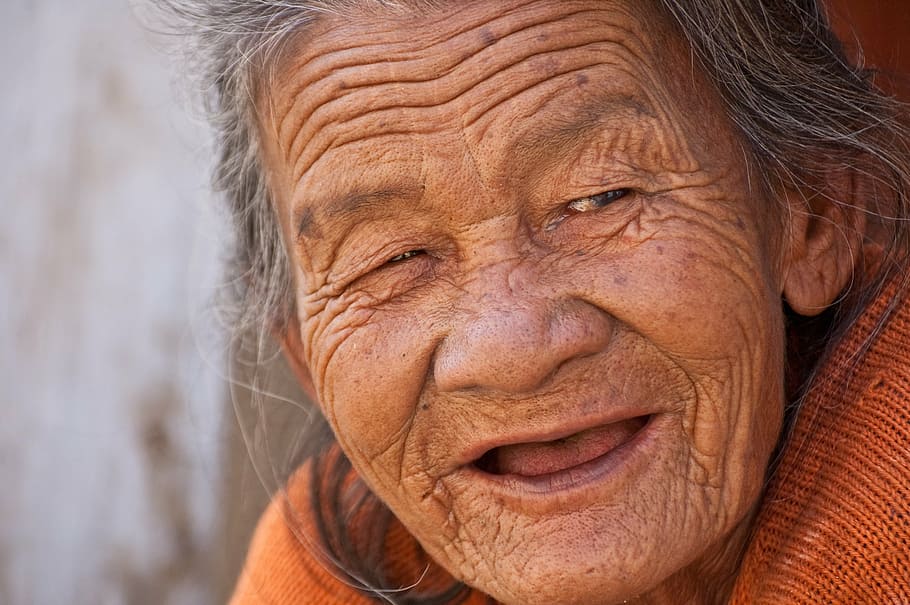 macro shot of person wearing orange knitted top, old lady, smile