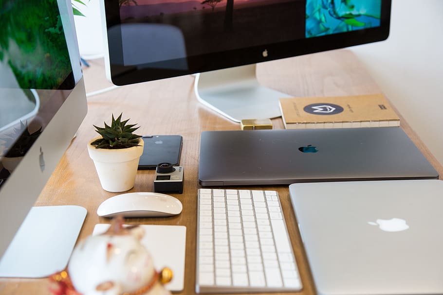 gray laptop computer on table near keyboard and monitors, apple HD wallpaper