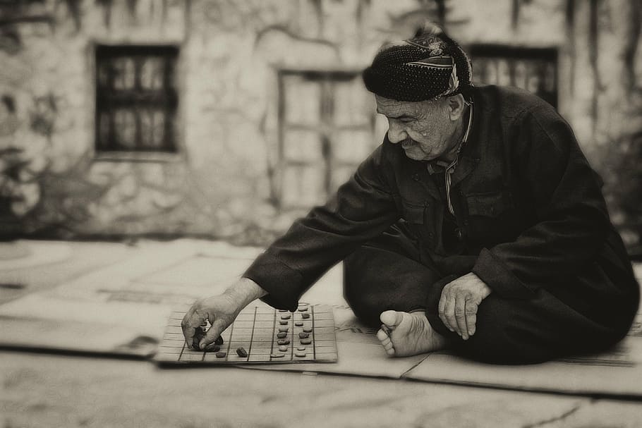 grayscale photography of man playing checkers, board game, old
