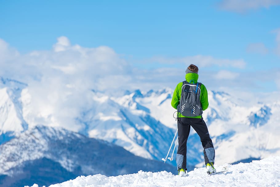 man standing on top of snow mountain, man in green jacket standing on mountain during daytime HD wallpaper