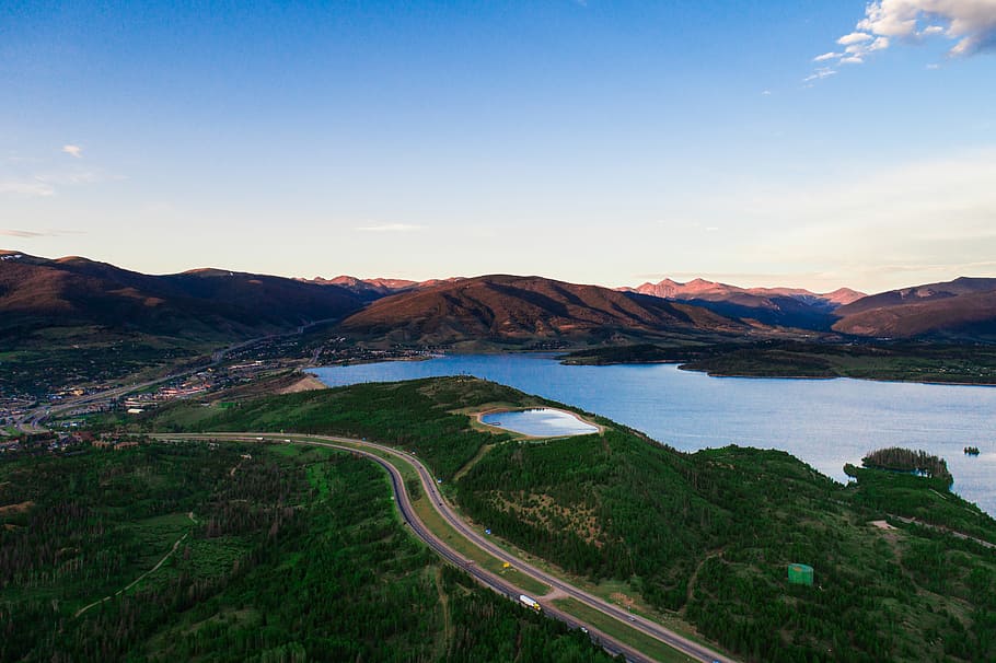 sea by the land, aerial view of road near body of water and mountains during daytime HD wallpaper