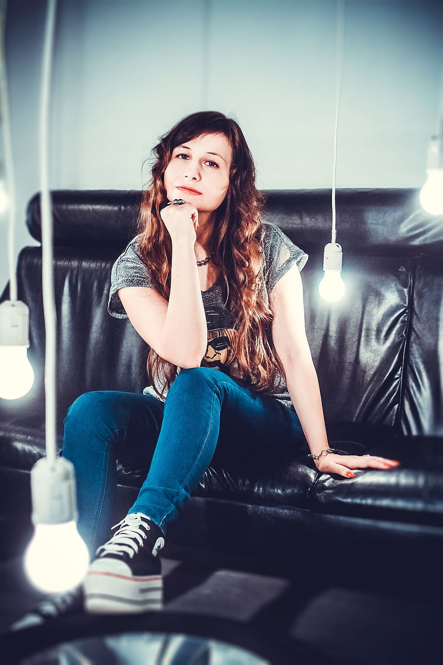 woman in gray top and blue jeans sitting on black leather couch HD wallpaper