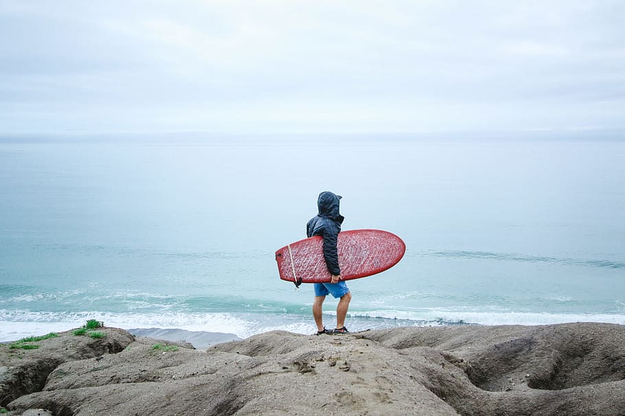 person holding surfboard, person holding red surfboard on seashore HD wallpaper