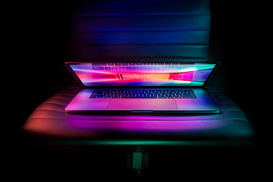 MacBook Pro showing pink and green wallpaper, silver and black laptop computer on leather chair HD wallpaper