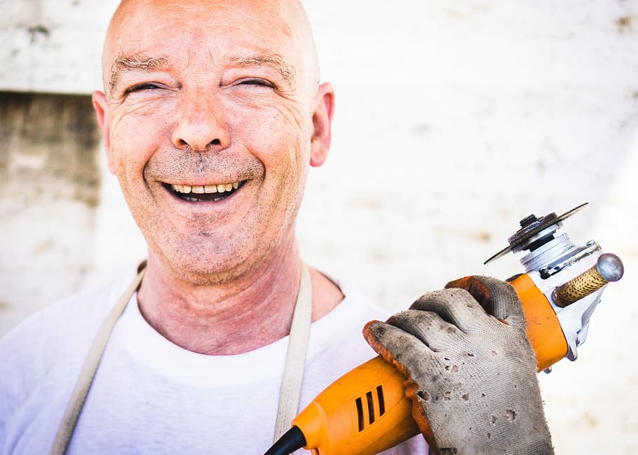 man holding yellow power tool smiling for photo, men, people HD wallpaper