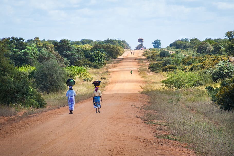woman walking on pathway during daytime, african women walking along road